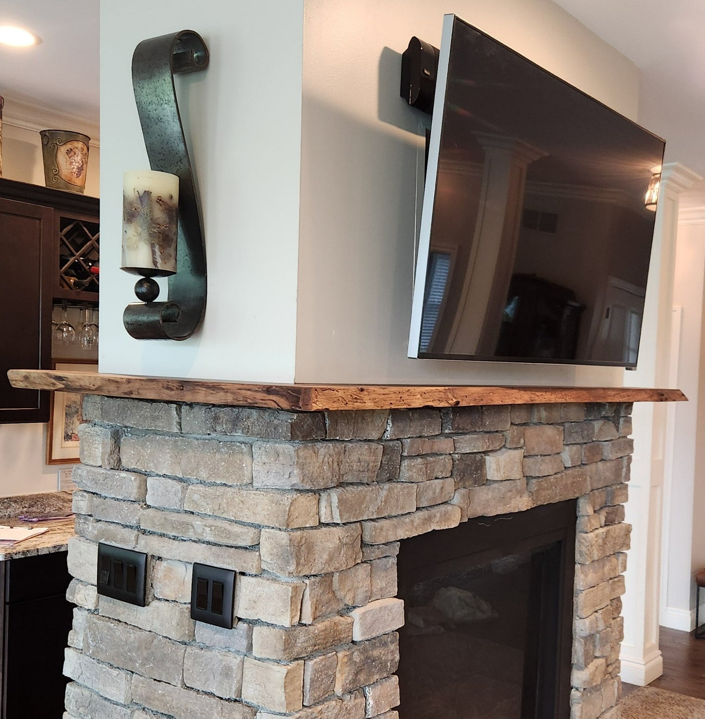 Live edge rustic walnut fireplace mantel above stone hearth