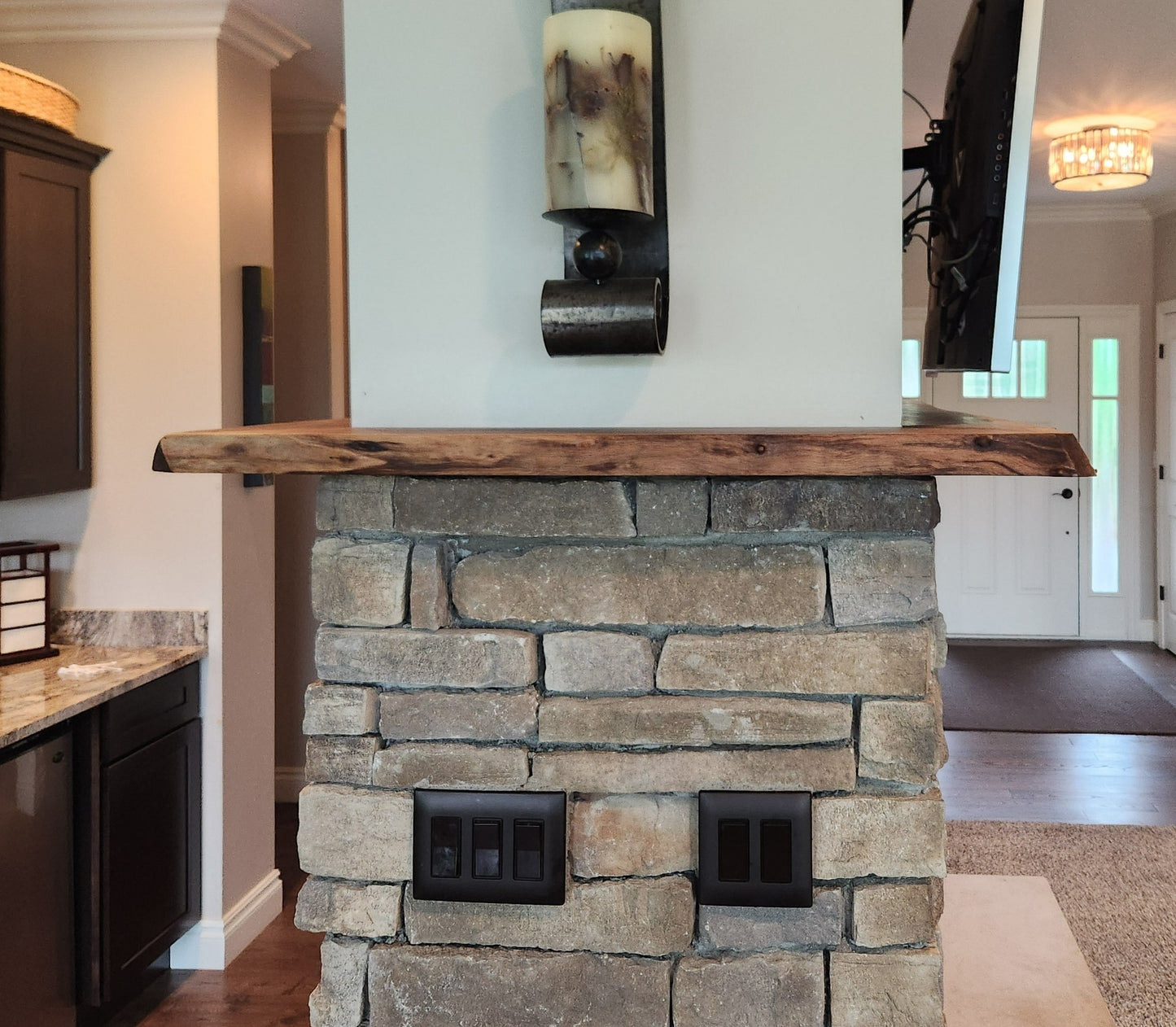 Live edge rustic walnut fireplace mantel above stone hearth