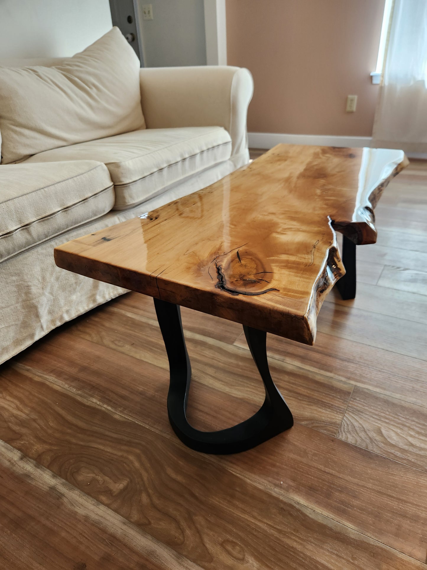 Knotty and rustic live edge cherry coffee table coated with clear epoxy with contemporary metal legs