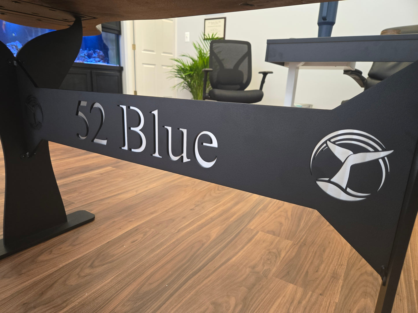 Walnut conference table shaped like a whale tail with blue epoxy river running down the center. Custom metal legs engraved with business name and logo.