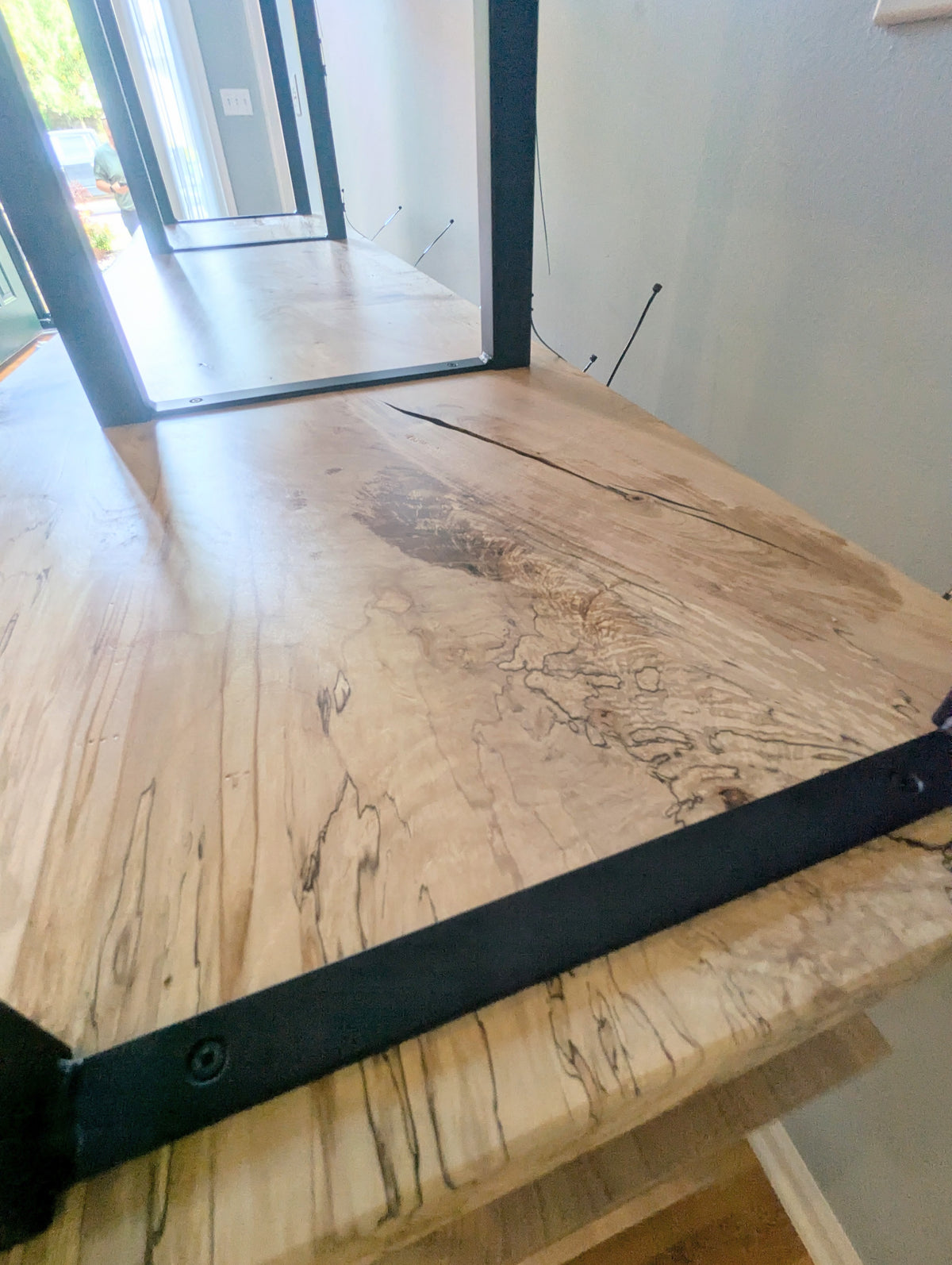 Live edge rustic ambrosia maple hardwood shelving unit with five shelves and custom fabricated black metal bars for storage of vinyl records, CDs, and corresponding players and speakers in a modern home living room.