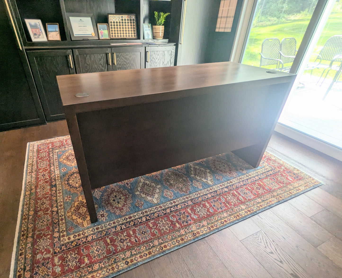 A modern stained cherry hardwood executive desk with waterfall style sides, grommets in the desk top and a hidden cord management shelf for clean storage.