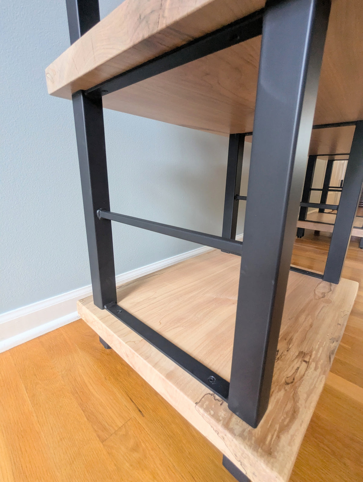 Live edge rustic ambrosia maple hardwood shelving unit with five shelves and custom fabricated black metal bars for storage of vinyl records, CDs, and corresponding players and speakers in a modern home living room.