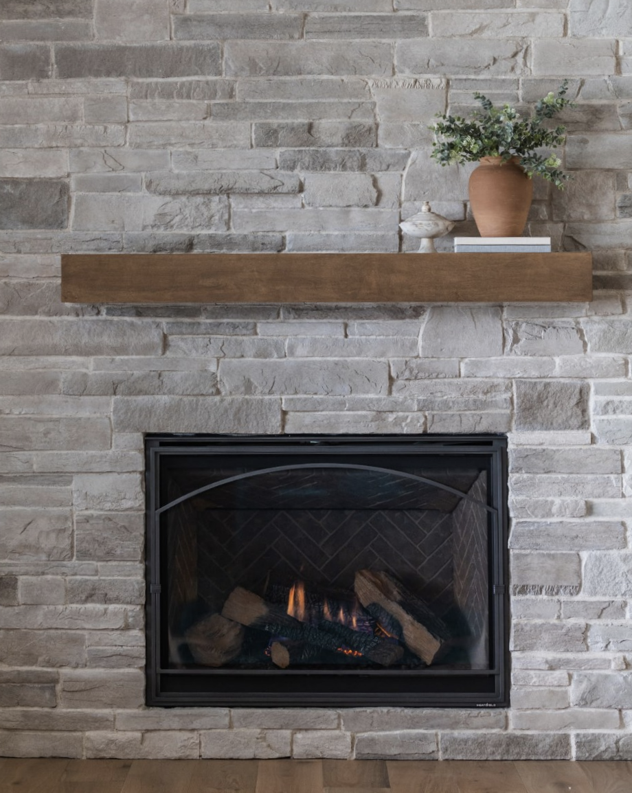 Stained maple floating fireplace mantel centered above stone hearth