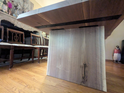 Rustic live edge walnut hardwood dining table with wood legs and a natural finish.