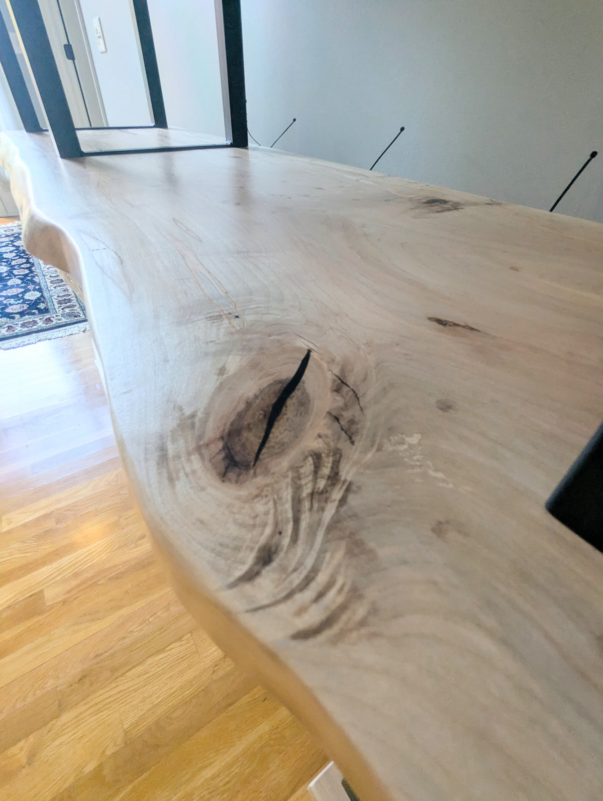 Live edge rustic ambrosia maple hardwood shelving unit with five shelves and custom fabricated black metal bars for storage of vinyl records, CDs, and corresponding players and speakers in a modern home living room.